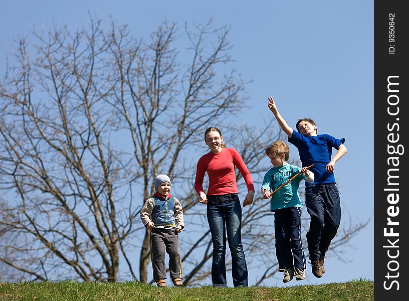 Four children jump on the green field.