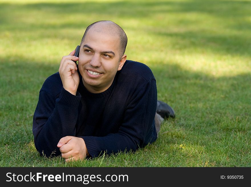 Young man lying on grass and talking on the mobile phone. Young man lying on grass and talking on the mobile phone
