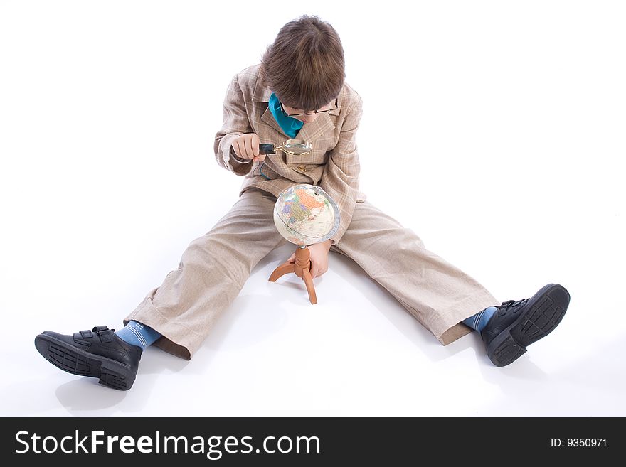 The boy of 6-years considers the globe through magnifying glass. The boy of 6-years considers the globe through magnifying glass