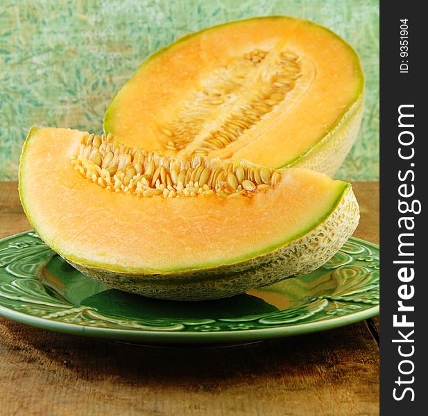 Sliced Cantaloupe on a wooden table with a green background.