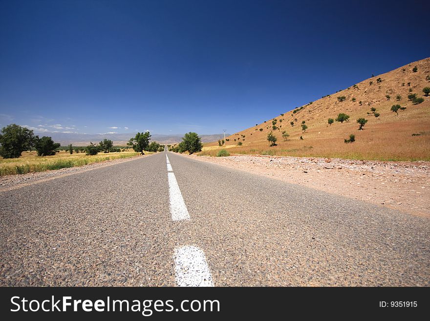 Beautiful road in Morocco with trees, sand, line and blue sky. Beautiful road in Morocco with trees, sand, line and blue sky
