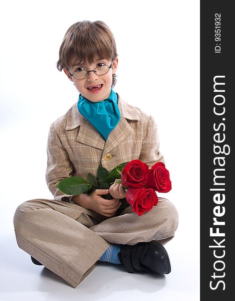 The boy of 7-years sits with a bouquet of roses looks in the chamber on the white isolated background. The boy of 7-years sits with a bouquet of roses looks in the chamber on the white isolated background