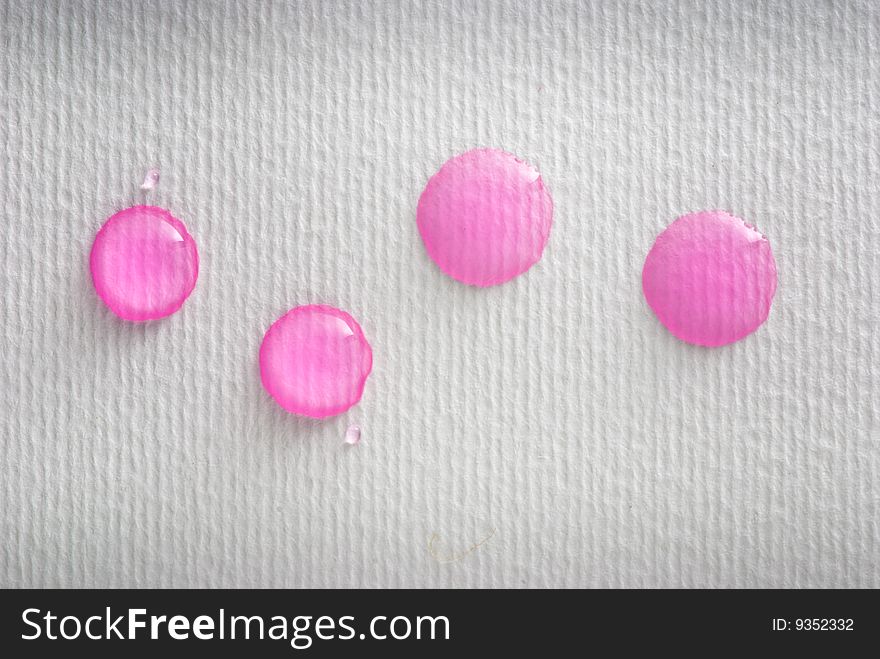 Four pink water drops on white paper