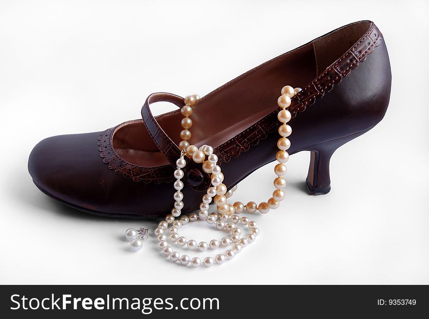 Brown high heel shoe with pearl necklaces and earrings. Brown high heel shoe with pearl necklaces and earrings
