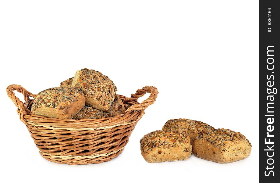 Fresh baked multi grain rolls in a wicker basket with three rolls to one side, over white backgound. Fresh baked multi grain rolls in a wicker basket with three rolls to one side, over white backgound.