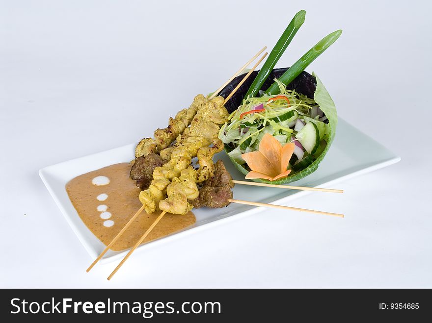 Beef and pork skewers with a salad isolated on a white background