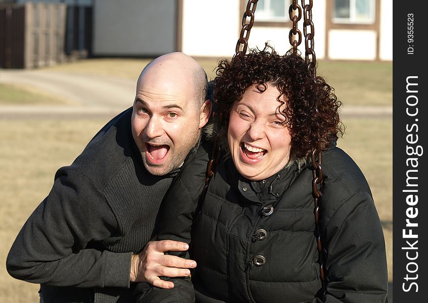 Young couple with funny expressions having fun on a swing outdoors. Young couple with funny expressions having fun on a swing outdoors.