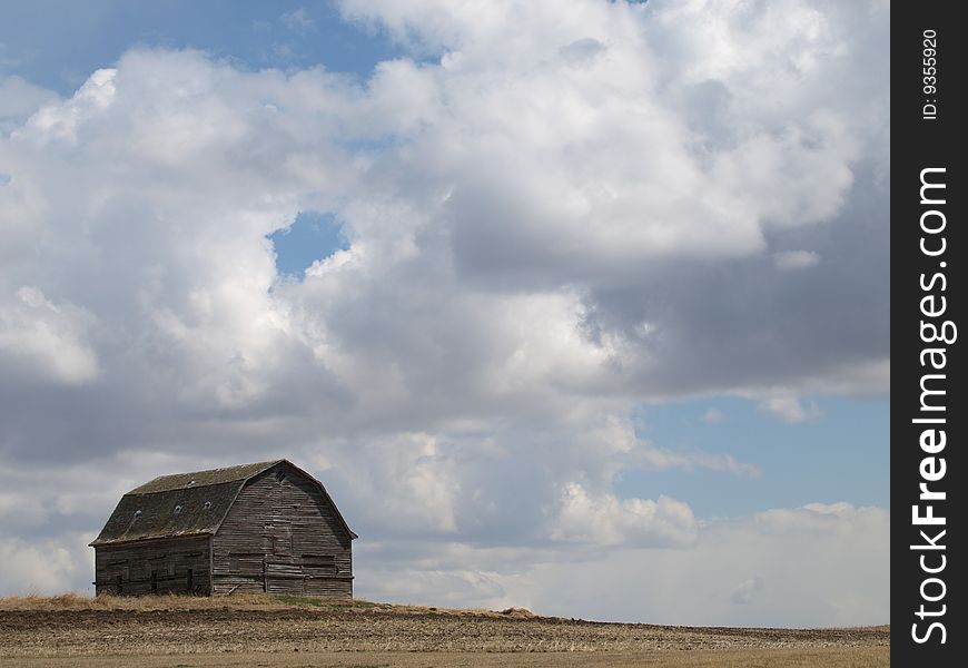 This old barn stands out stark against the sky with the puffy white clouds. This old barn stands out stark against the sky with the puffy white clouds.