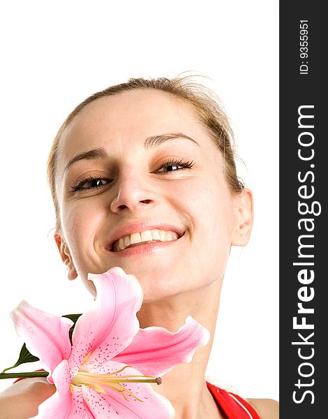 A portrait of a smiling nice blond girl with a pink lily near her face on a white background. A portrait of a smiling nice blond girl with a pink lily near her face on a white background