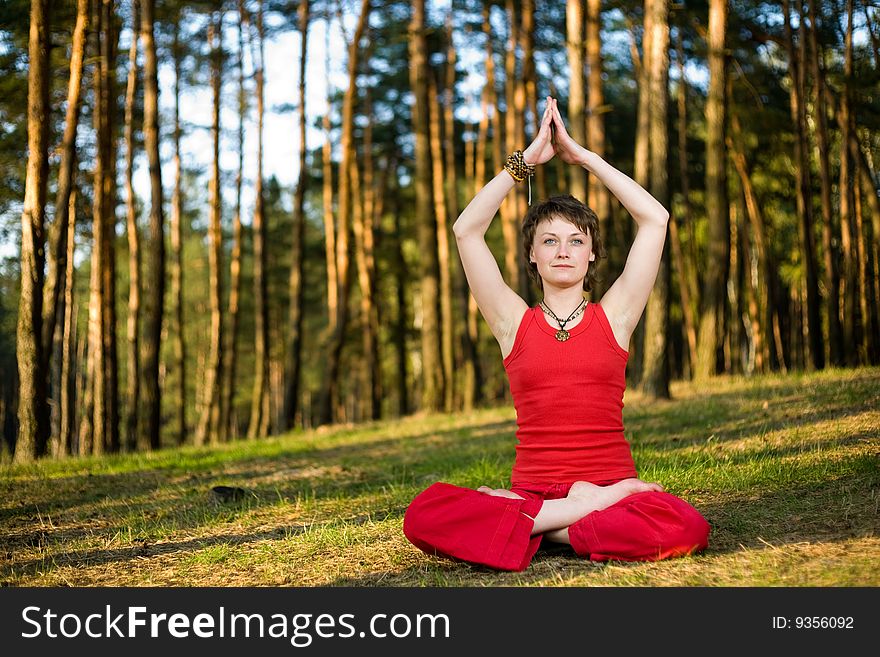 A young pretty woman sitting in lotos pose on the forest background