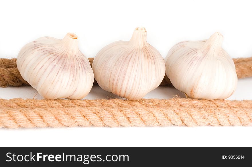 Three bulbs of garlic near the rope on the white background