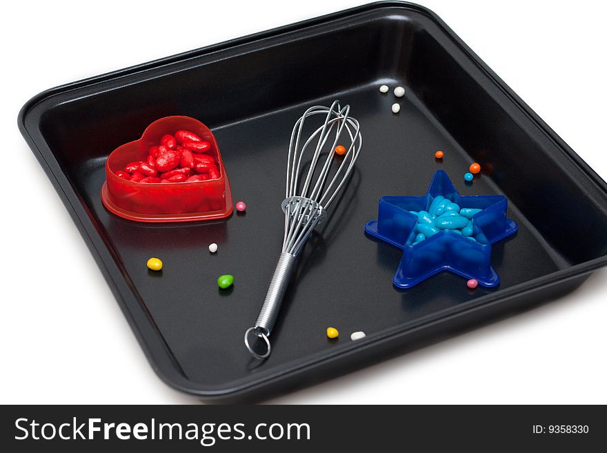 Form for baking, plastic red heart with sweetmeat and blue star, on white background