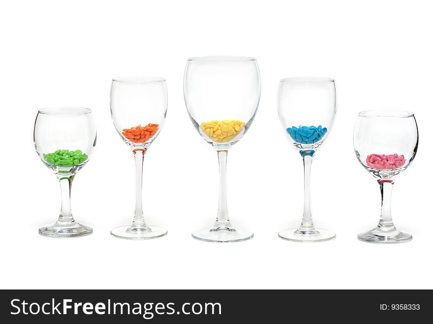 Tall wine glasses exposed in row on white background with colour sweetmeat. Tall wine glasses exposed in row on white background with colour sweetmeat