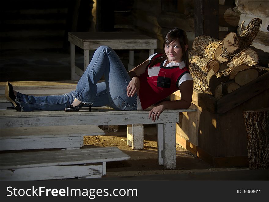 A teen girl kicks back on an old bench in a rustic log cabin. A teen girl kicks back on an old bench in a rustic log cabin.