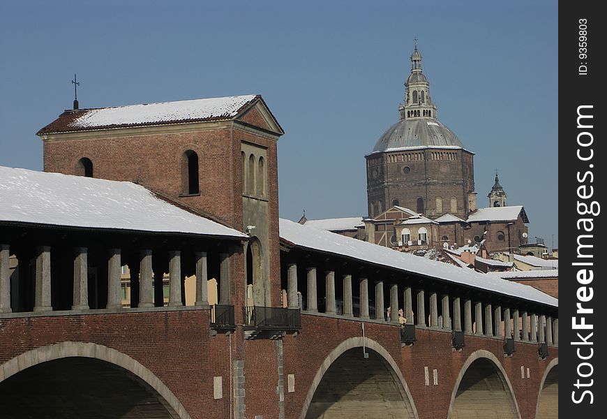 The bridge and the cathedral of Pavia (Italy) covered by snow.