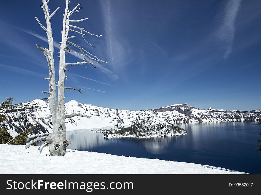Deep blue lake with surrounding snow and a view of Wizard Island. Deep blue lake with surrounding snow and a view of Wizard Island.