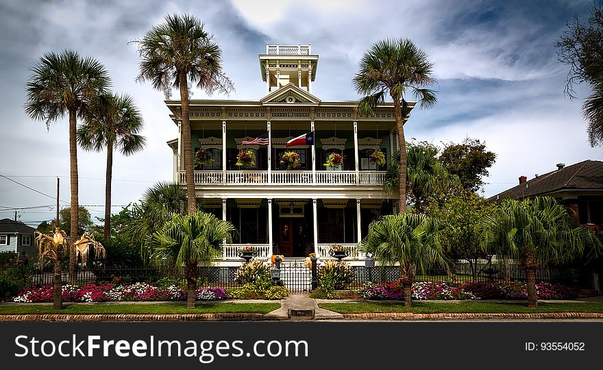 White Painted Structure With Green Palm Trees in the Front