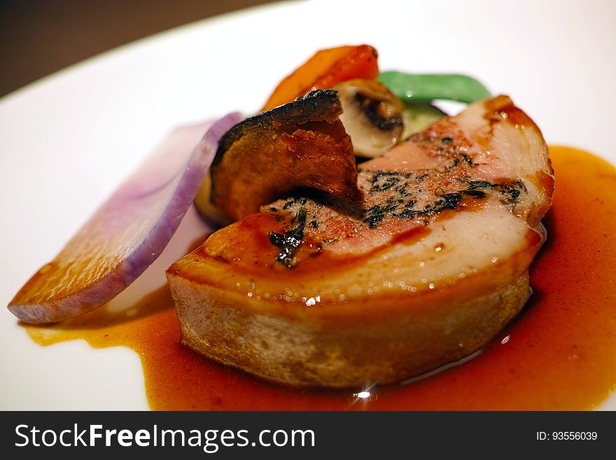 A plate of duck liver with vegetable garnish.