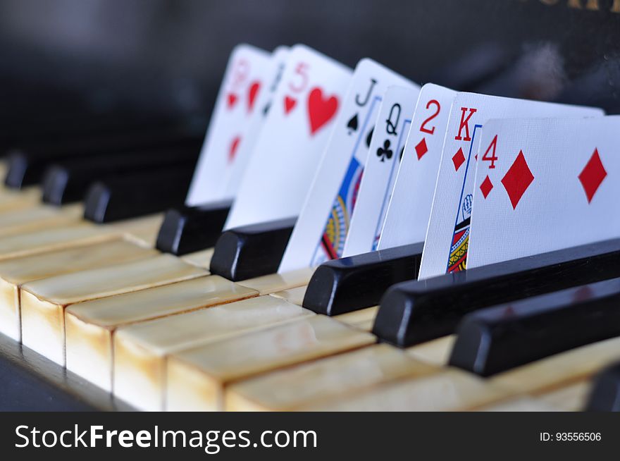 Closeup of playing cards in between piano keys.