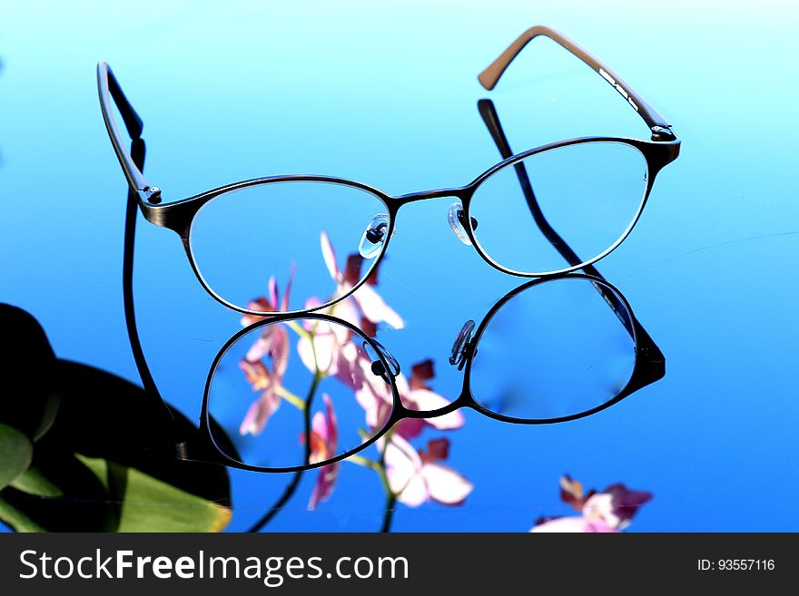 A pair of eyeglasses on a mirror surface. A pair of eyeglasses on a mirror surface.