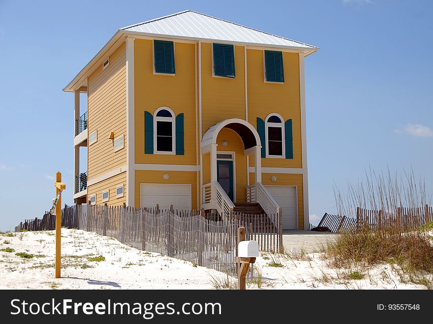 Tall modern home by sandy beach with blue sky background. Tall modern home by sandy beach with blue sky background.