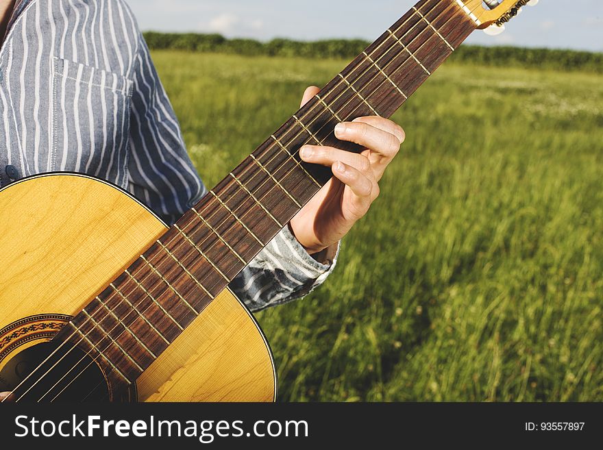 A man playing a guitar on a field in the summer. A man playing a guitar on a field in the summer.