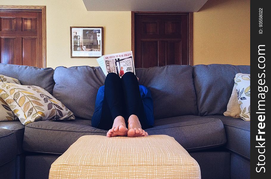 A person sitting on a sofa reading a book. A person sitting on a sofa reading a book.