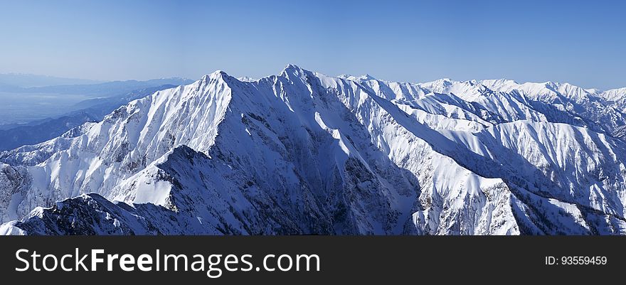 Cold mountain landscape with sunlit areas and areas in shadow, a challenge to both climbers and dedicated mountaineers, pale blue sky. Cold mountain landscape with sunlit areas and areas in shadow, a challenge to both climbers and dedicated mountaineers, pale blue sky.