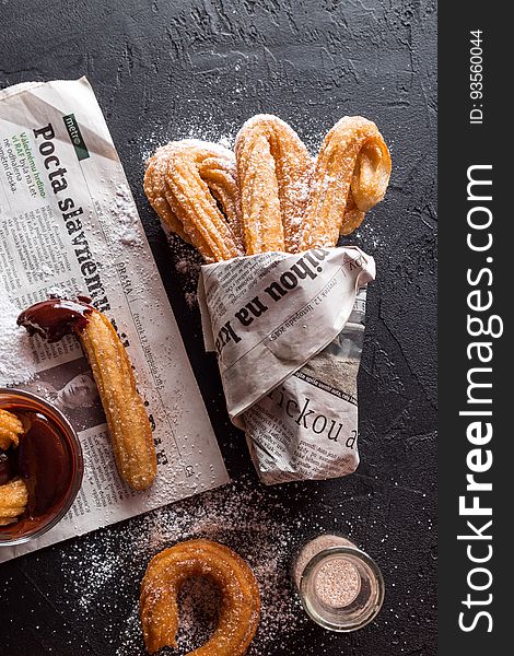 Freshly baked churros wrapped in newspaper.