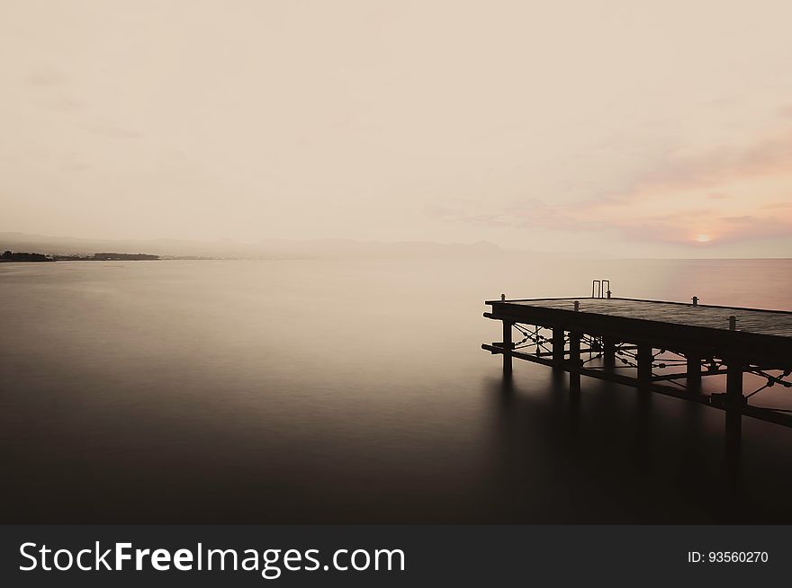 A seascape with a jetty at sunset.