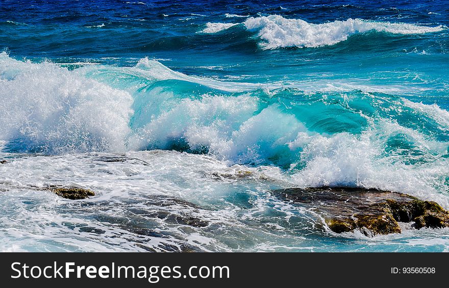 A view of the shore with blue colored waves hitting rocks. A view of the shore with blue colored waves hitting rocks.
