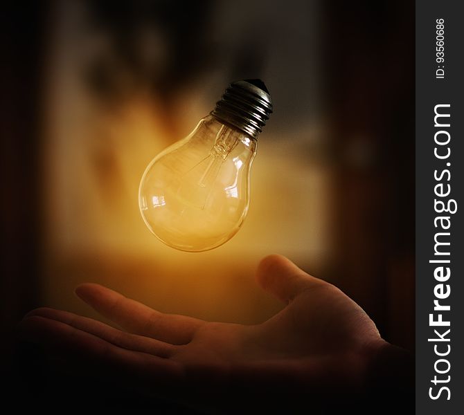 A close up of a light bulb levitating above a hand. A close up of a light bulb levitating above a hand.