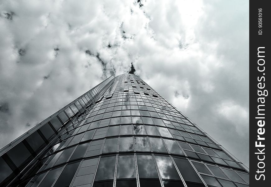 A glass skyscraper against the cloudy skies.