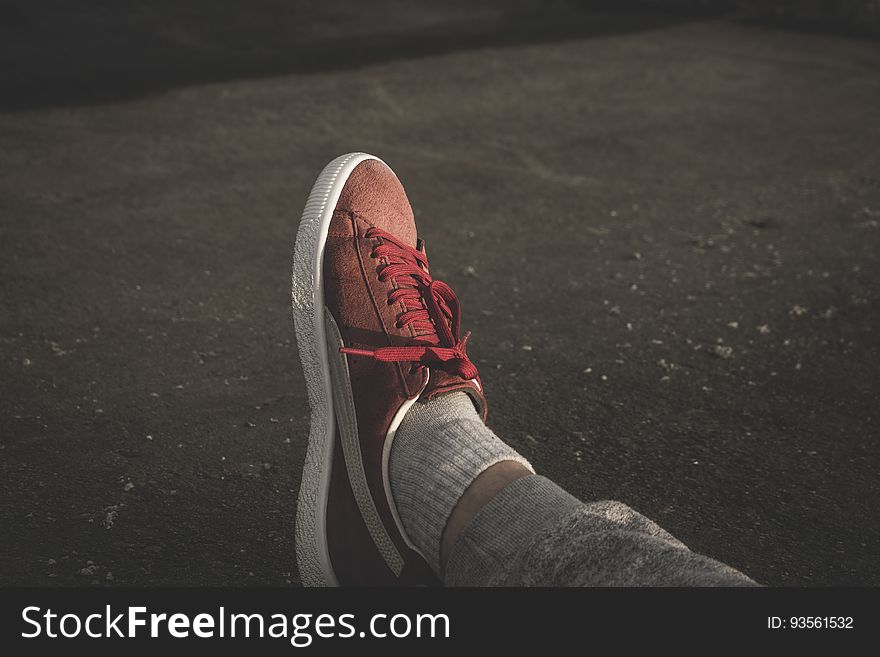 A close up of a foot in a sneaker resting on the ground. A close up of a foot in a sneaker resting on the ground.