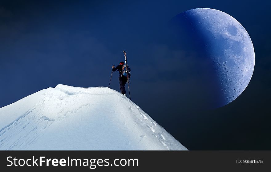 A mountain climber reaches the top of a mountain summit. A mountain climber reaches the top of a mountain summit