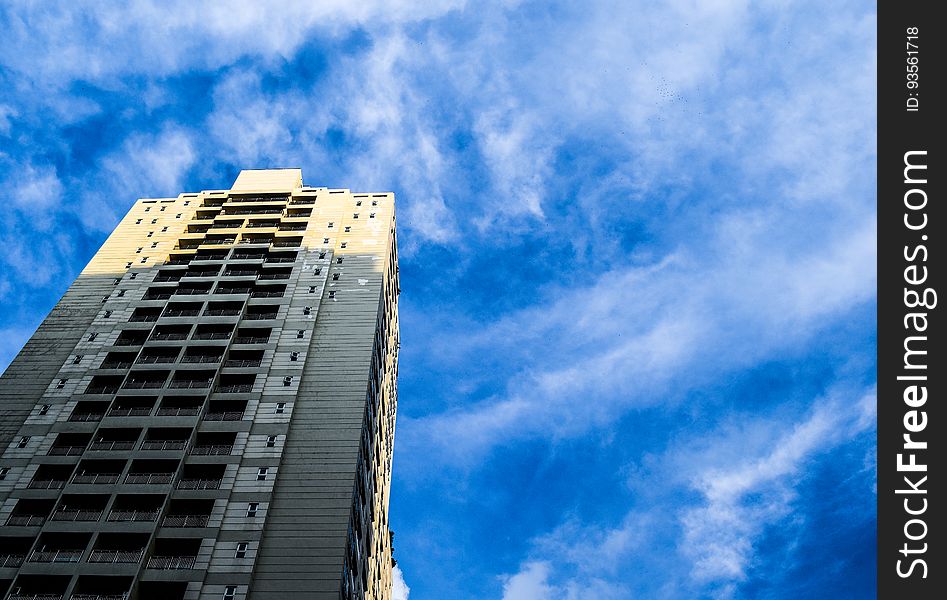 High rise contemporary building against blue skies with wispy clouds on sunny day. High rise contemporary building against blue skies with wispy clouds on sunny day.