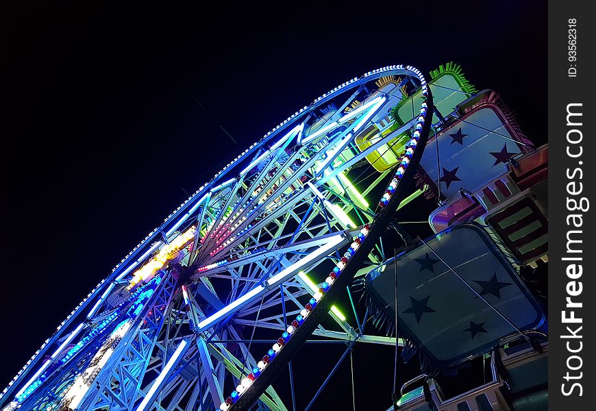 A colorful Ferris wheel seen from below at night.