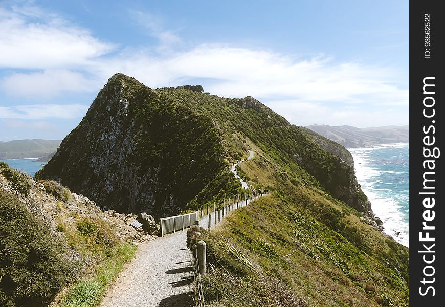 Empty path along hillside ridge overlooking coastline on sunny day. Empty path along hillside ridge overlooking coastline on sunny day.