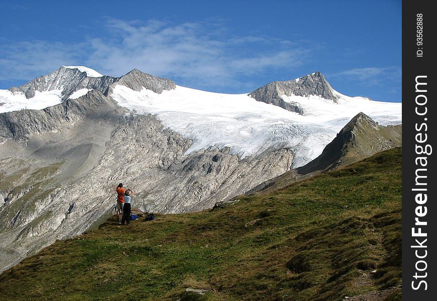 People On Green Grass Near Snow Mountain Under Blue Sky During Daytime