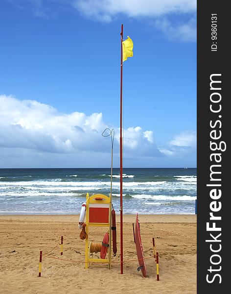 A beach with a lifeguard station flying a yellow flag, under a part cloudly sky with the tide coming in. A beach with a lifeguard station flying a yellow flag, under a part cloudly sky with the tide coming in.