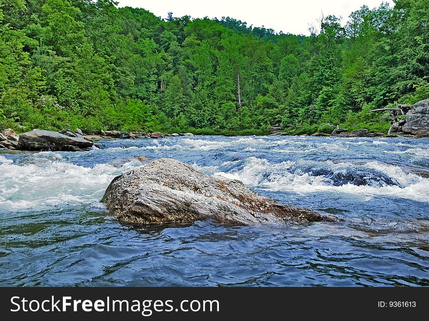 A bolder in the middle of a swiftly flowing river. A bolder in the middle of a swiftly flowing river.