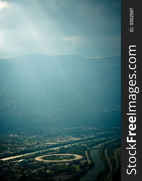 Image of a mountain valley with atmospheric lighting, and a view of the Grenoble particle accelerator (Cyclotron). Image of a mountain valley with atmospheric lighting, and a view of the Grenoble particle accelerator (Cyclotron).