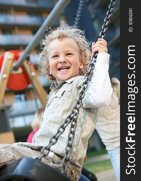 A little boy having a great time on a swing in a playground. A little boy having a great time on a swing in a playground.