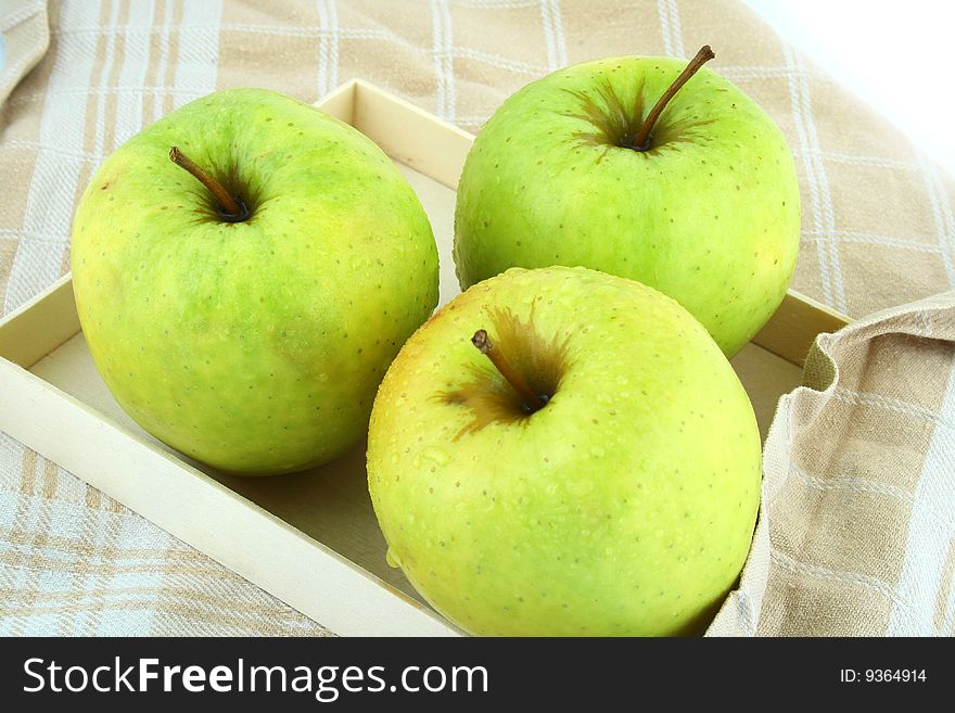 Three green apples on square dish isolated on white