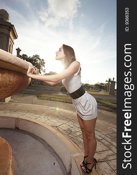 Young woman on her toes looking in a fountain. Young woman on her toes looking in a fountain