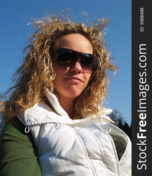 Curly girl with sunglasses in white vest