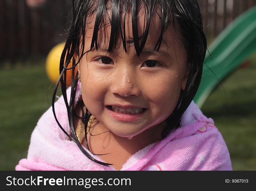 Little Asian Chinese Girl Dripping with water with a smile and a towel around her. Little Asian Chinese Girl Dripping with water with a smile and a towel around her