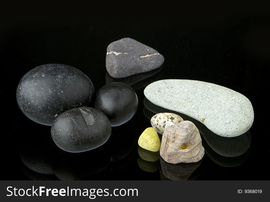 A collection of different shape, natural stones on top of a glass with reflection