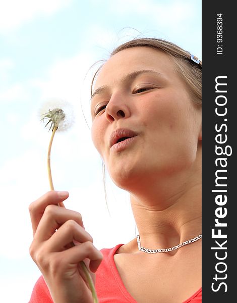 Happy young girl poses in front of the camera with a dandelion