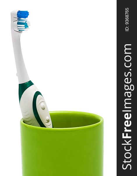Toothbrush in a green glass on a white background